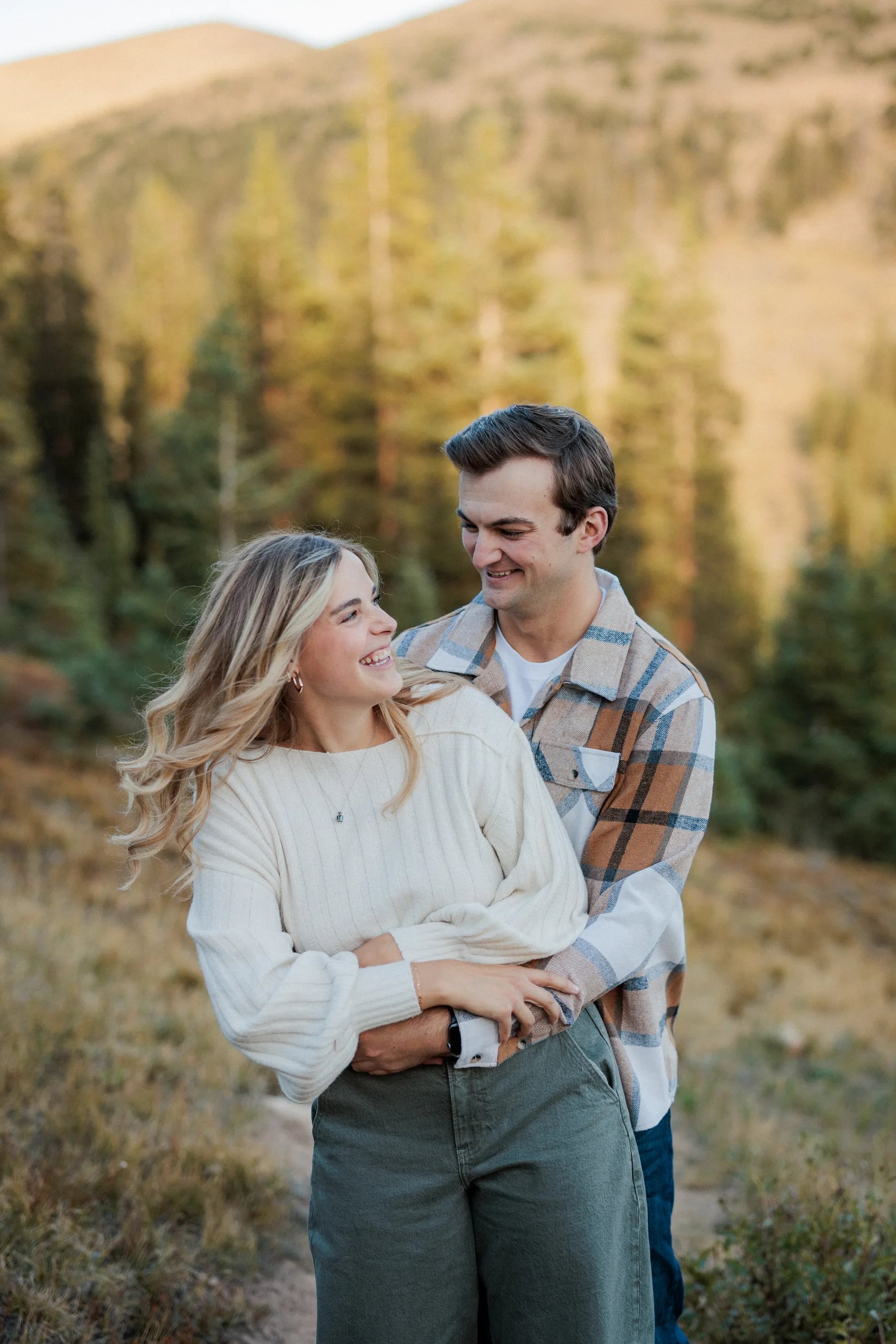 Jordan and Daelynn laughing together in a fall mountain meadow